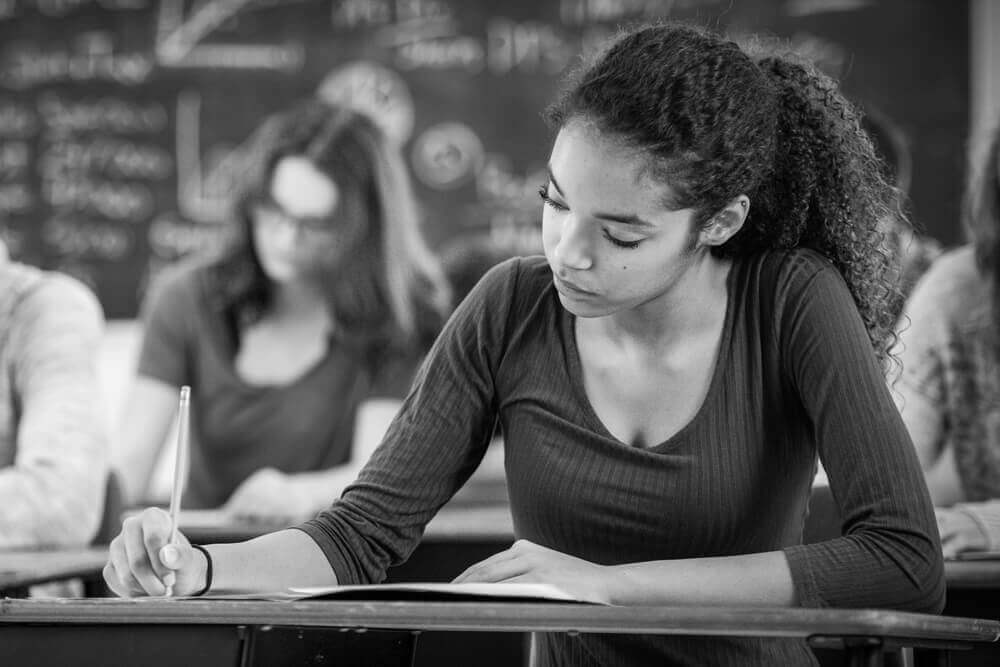 This is a photo of a young woman taking notes in a classroom setting