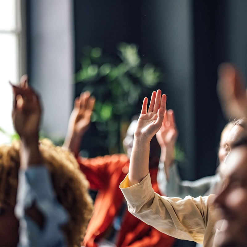 Professionals raising hand to answer question at conference